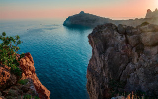 Rocky cliff ocean island boat - a small island in the distance free wallpaper
