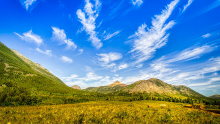 Mountain range blue sky clouds 5 - a grassy field below free wallpaper