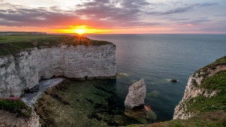Sunset cliff rocks water boat - a sunset over a rocky cliff free wallpaper