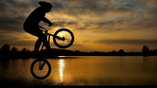 Sunset bike over lake backlighting - a man riding free wallpaper