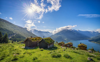Grassy field house lake mountains - a bright sun free wallpaper