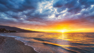 Sunset ocean beach mountains cloudy - a sun setting free wallpaper