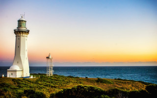 Lighthouse grassy hill ocean sunset - a blue ocean free wallpaper