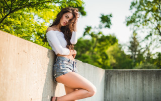 Woman leaning wall crossed legs 4 - prima free wallpaper