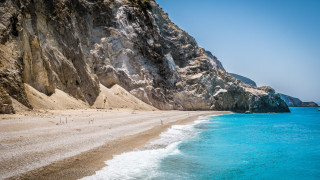 Beach mountain water person sand - a mountain in the background and a body of water free wallpaper