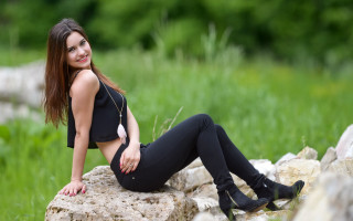 Woman sitting rock black top - black pants free wallpaper