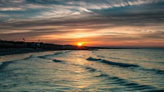 Sunset ocean waves boat cityscape - a boat in the distance free wallpaper