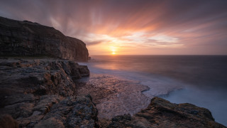 Sunset rocky beach water cliff 7 - a sunset over a rocky beach free wallpaper