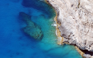 Rocky cliff blue water aerial - exekia free wallpaper