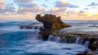 Waterfall ocean rocks cloudy sunset - a rock formation in the foreground free wallpaper for desktop
