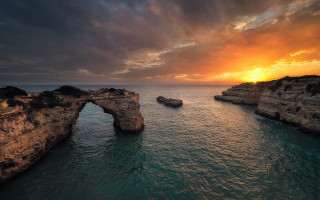Sunset water rock arch beach - a rock formation in the middle of it free wallpaper