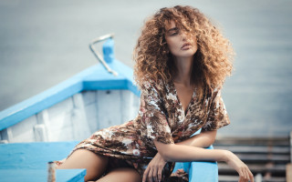 Woman blueboat crossedlegs curlyhair blurryphotorealistic - a blue boat free wallpaper