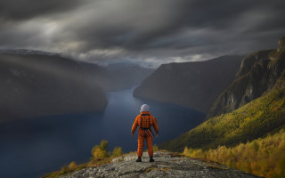 Man orange suit cliff lake - photography free wallpaper
