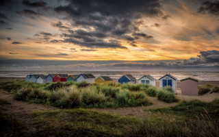 Beach huts grass ocean cloudy - the ocean under a cloudy sky free wallpaper