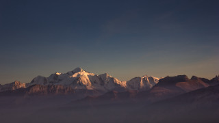 Mountain range snow capped cliffs - a few cloud below free wallpaper
