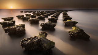 Sunset rocks water bridge cityscape - the sun setting behind them free wallpaper for desktop