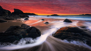 Sunset beach rocks water mountains - a red sky in the background free wallpaper for desktop
