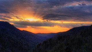 Sunset mountain forest cloudy sunbeam - a sunset over a mountain range free wallpaper