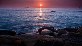 Sunset ocean boat rocks coastline - a boat in the distance free wallpaper