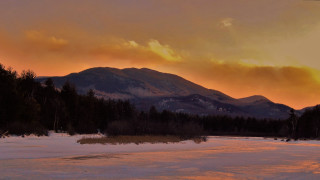 Sunset mountain range snowy field - a sunset view of a mountain range free wallpaper