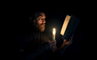 Man holding book candle dark - chiaroscuro free wallpaper