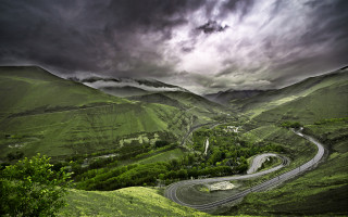 Winding road green valley cloudy - a lush green valley under a cloudy sky free wallpaper