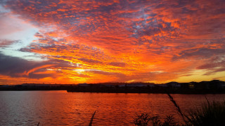 Sunset water clouds building horizon - a sunset over a body of water free wallpaper