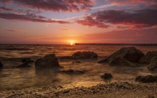 Sunset water rocks bridge cityscape - a sunset over a body of water free wallpaper