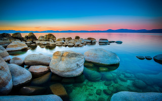 Rocky shore sunset mountains ocean - the water and a sunset in the background free wallpaper