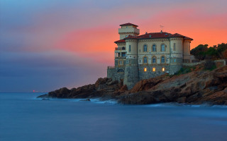 Cliffside mystical building sunset ocean - a pink sky free wallpaper
