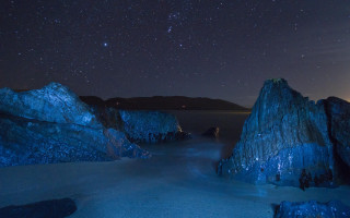Night sky stars water rocks - the shore of a beach free wallpaper