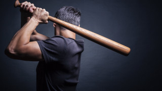 Man holding bat over shoulder - a dark background behind free wallpaper