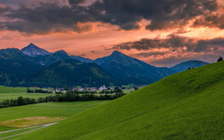 Green field mountain sunset cityscape - a mountain range in the background free wallpaper