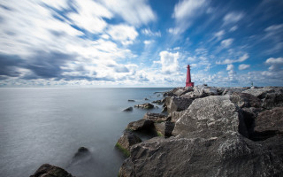 Red lighthouse rocky shore cloudy - a body of water below free wallpaper