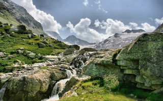 Lush green valley stream mountains 3 - a lush green valley under a cloudy sky free wallpaper