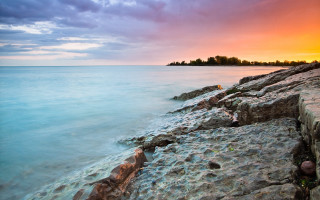 Rocky shore sunset island city - a small island in the distance free wallpaper
