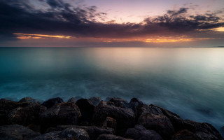 Rocky shore sunset water mountains - a sunset in the background and a body of water free wallpaper