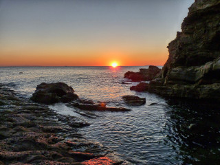 Sunset ocean rocks boat clouds - the foreground and a boat in the distance free wallpaper