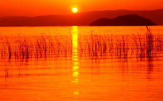 Sunset water boat mountain orange - a sunset over a body of water free wallpaper