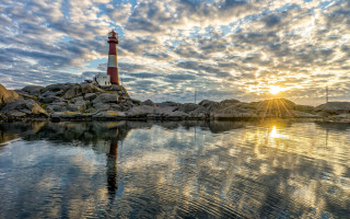 Lighthouse rocky shore sunset clouds 4 - the sun setting behind free wallpaper