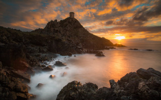 Lighthouse rocky cliff sunset ocean 2 - a sunset in the background and a body of water free wallpaper