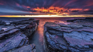 Sunset rocky beach water formation - a large rock formation in the foreground free wallpaper