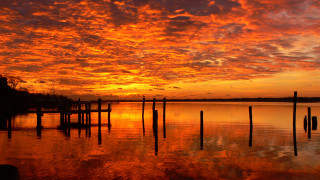 Sunset water dock poles mountains - a sunset over a body of water free wallpaper
