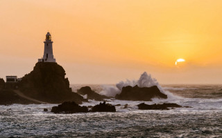 Lighthouse rocky shore waves sunset - a sun setting free wallpaper