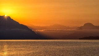 Sunset mountain water boat sky - a sunset over a body of water free wallpaper