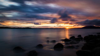 Sunset water rocks mountain clouds - a sunset over a body of water free wallpaper