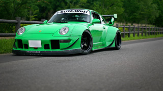 Green sports car driving road - a fence and trees free wallpaper
