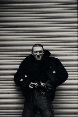 Man standing garage door smiling - his hands in his pockets free wallpaper