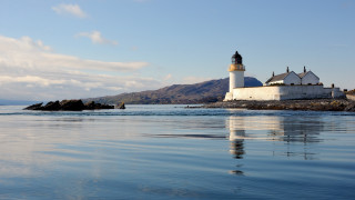 Lighthouse rocky shore mountains water - a body of water in front free wallpaper