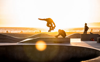 Skateboarder flying sunset beach ocean - a skateboard free wallpaper